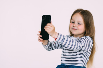 Portrait of an excited little girl taking a selfie isolated on white background