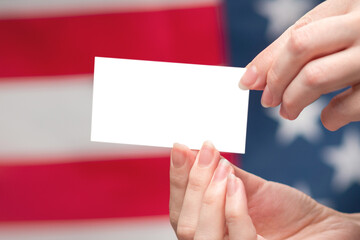 Obraz premium Empty card in woman hand. Copy space. American flag background.