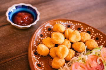 Palomitas de pollo con ensalada y contenedor con salsa catsup