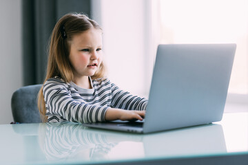 Cute little girl smiling and looking at laptop. Little girl using laptop