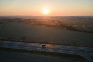 Aerial view of intercity road with blurred fast driving car at sunset. Top view from drone of...