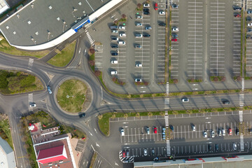 Aerial view of many colorful cars parked on parking lot with lines and markings for parking places and directions