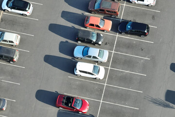 Aerial view of many colorful cars parked on parking lot with lines and markings for parking places and directions - obrazy, fototapety, plakaty
