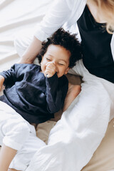 studio photo of a little dark-skinned boy dressed in comfortable linen clothes. child in mother's arms