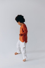 Fototapeta na wymiar Stylish portrait of a curly dark-skinned 3-year-old boy dressed in stylish linen clothes