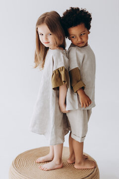 Photos of children having fun and posing for a photo in summer linen clothes in a photo studio. Dark-skinned boy and caucasian girl together in the photo