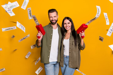 Photo of young cheerful husband wife shoot money benefit profit isolated over yellow color background