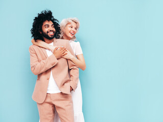 Smiling beautiful woman and her handsome boyfriend. Sexy cheerful multiracial family having tender moments on blue background in studio. Multiethnic models hugging. Embracing each other.Love concept