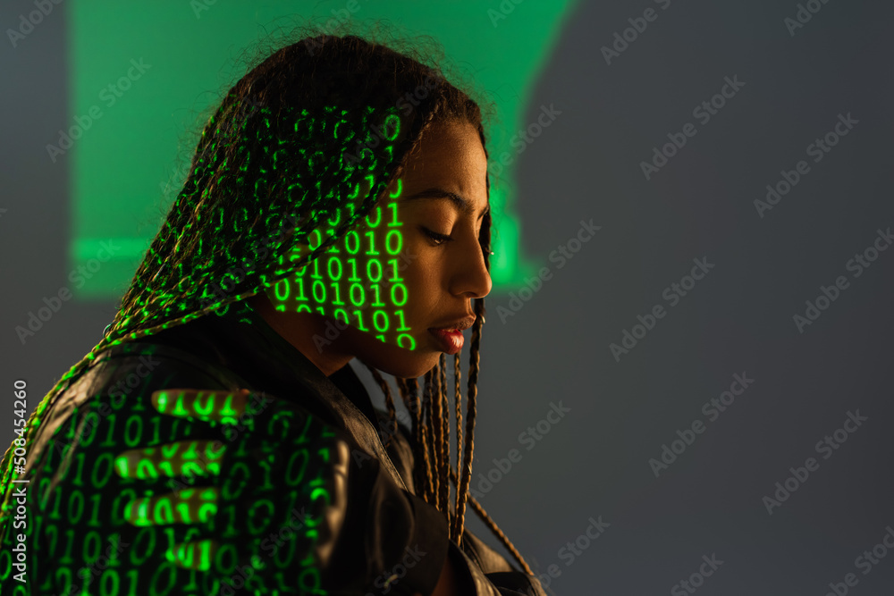 Wall mural side view of african american woman with projection of binary code on grey background.