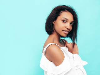 Closeup portrait of young beautiful black woman. Smiling model dressed in summer jeans clothes. Sexy carefree female posing near blue wall in studio. Tanned and cheerful