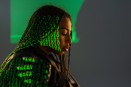 Side view of african american woman with projection of binary code on grey background.