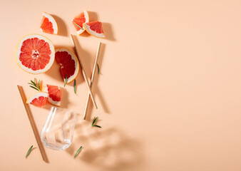 Grapefruit slices, rosemary, straws, and an empty glass.