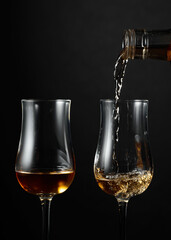 Strong alcohol drink is poured from a bottle into a glass.