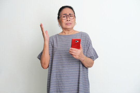 Elderly Asian Woman Showing Confused Expression When Holding A Mobile Phone