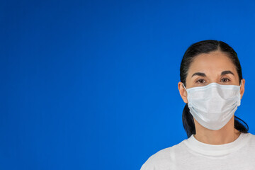 Isolated Woman wearing protective mask against blue background, copy space