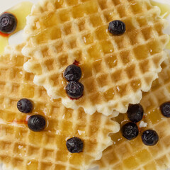 Close up of round belgian waffles with honey and blueberries, top view. Thin golden waffle cookie,...
