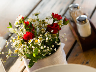 Bouquet of roses, daisies and other wild flowers as wedding decoration on a wooden table