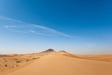 Fototapeta na wymiar Sand Dunes landscape with Mountains in the background and with blue sky with large copy space
