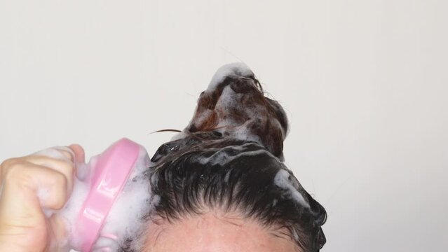 4k video hair growth stimulating, scalp massage.woman using pink scalp massager shampoo brush with silicone,flexible bristels.hair care,head relaxation.shampoo foam on hair,hand,isolated