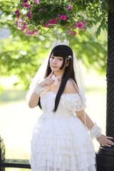 Beautiful young woman with white lolita dress with european garden Japanese fashion