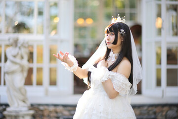 Beautiful young woman with white lolita dress with european garden Japanese fashion