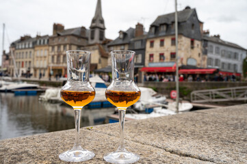 Tasting of apple calvados drink in old Honfleur harbour with boats and old houses on background, Normandy, France