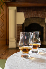 Two glasses of scotch whiskey with view on fireplace in old house on background, Edinburgh whisky tasting tour, Scotland