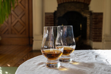 Two glasses of scotch whiskey with view on fireplace in old house on background, Edinburgh whisky tasting tour, Scotland