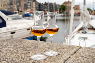 Tasting of apple calvados drink in old Honfleur harbour with boats and old houses on background,...