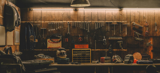 Workshop scene. Old tools hanging on wall in workshop, Tool shelf against a table and wall, vintage garage style