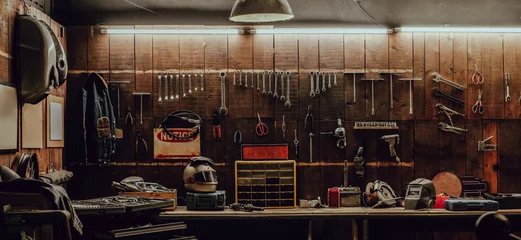 Fototapeten Workshop scene. Old tools hanging on wall in workshop, Tool shelf against a table and wall, vintage garage style © Win
