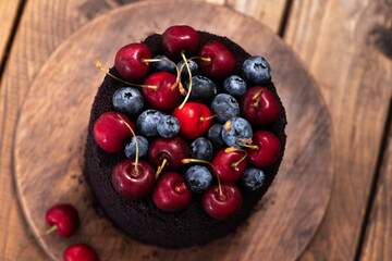 Dark cake with berries on top. A cake decorated with blueberries and cherries.