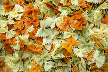 Pasta as a background. Cooked italian pasta Farfalle with oil. Colored pasta texture background. Top view. Tricolor pasta. Close up. Background carbohydrates food.