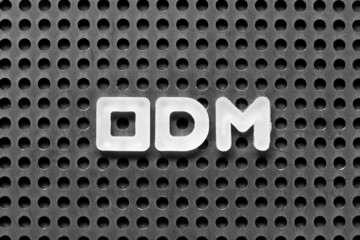White alphabet letter in word ODM (Abbreviation of Original design manufacturer) on black pegboard...
