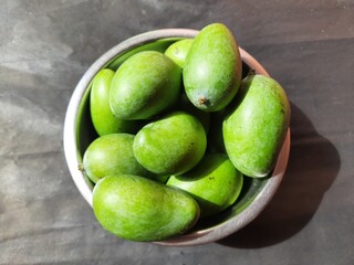 Raw mango in black background. Mango is a popular fruit, it is also called the king of fruits.  Its pickle is very tasty. It is cooked and made into vegetables. Green Mango in black background. 
