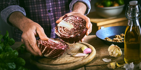Crop man halving red cabbage