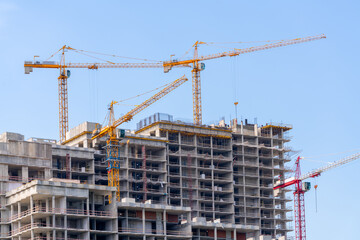 Construction cranes near the facade of a house under construction. modern building industry. Sale and rental of real estate.