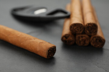 Cigars wrapped in tobacco leaves on black table, closeup