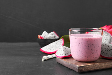 Delicious pitahaya smoothie and fresh fruits on black table, space for text