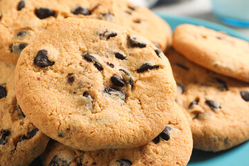 Many delicious chocolate chip cookies on plate, closeup