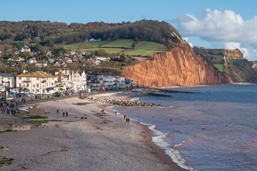 The pebble beach at Sidmouth, Devon UK  is a popular attraction for locals and holidaymakers alike. It is seen here against the sandstone cliffs of Pennington Point in the background - obrazy, fototapety, plakaty