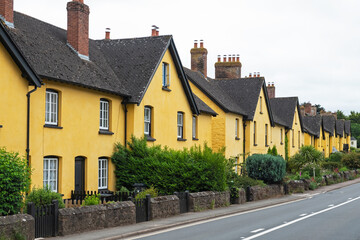 A row of vividly painted cottages lining a village roadside in East Devon, UK