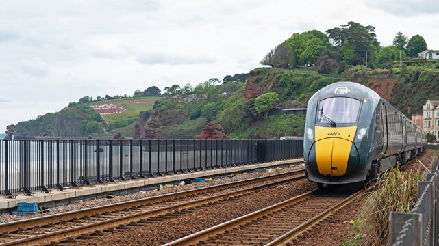 Dawlish, England - May 12, 2022: A Great Western Railway passenger train bound for London Paddington approaching  the station. The track at the resort has been reinforced after severe storm damage