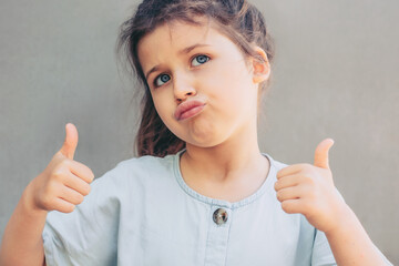 Narcissistic child girl proud of herself, schoolgirl shows thumbs up gesture.I am glamorous and cool