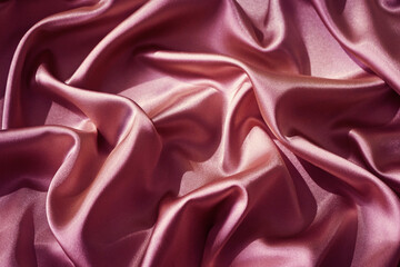 Pink silk satin. Shiny fabric surface. Wavy folds. Beautiful background with space for design.