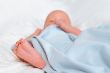 The foot of a newborn baby peeks out from under a blue blanket
