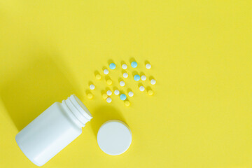 White pills and white bottle with copy space on yellow background, Healthy and Medicine concept.,colorful pills and drugs in close up.assorted pills and capsules in medicine. drugs of various kinds an