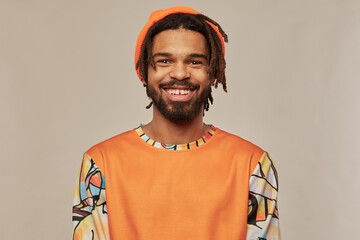Studio portrait of young african american man posing over studio background looking into camera with broad smile on his face