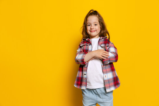 Happy little girl, kid wearing warm plaid shirt isolated on bright yellow background. Concept of children emotions, fashion, beauty, school and ad concept