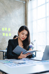 Attractive Asian Business Woman reading accounting notebook, income and expenses account.